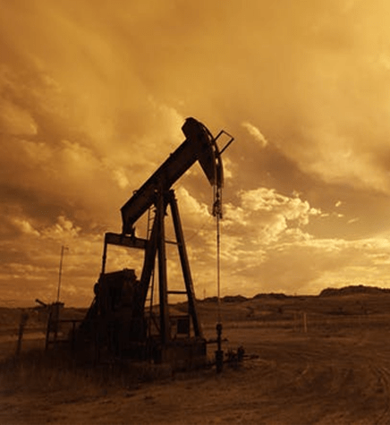An oil pump in the desert at sunset.
